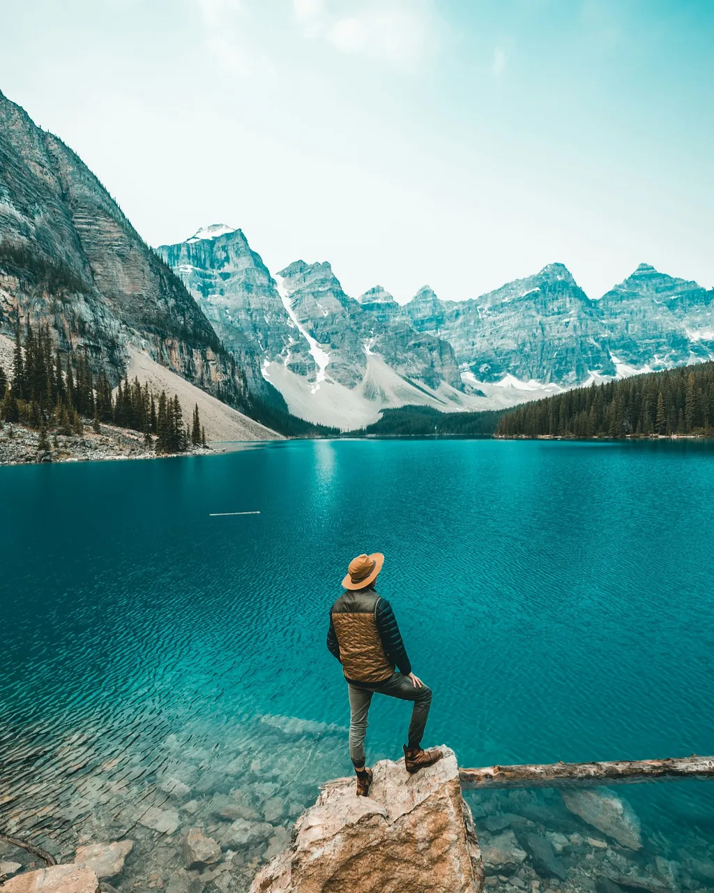Una persona amb barret contempla Moraine Lake des d'una roca, amb els cims de la vall dels Deu Pics al fons